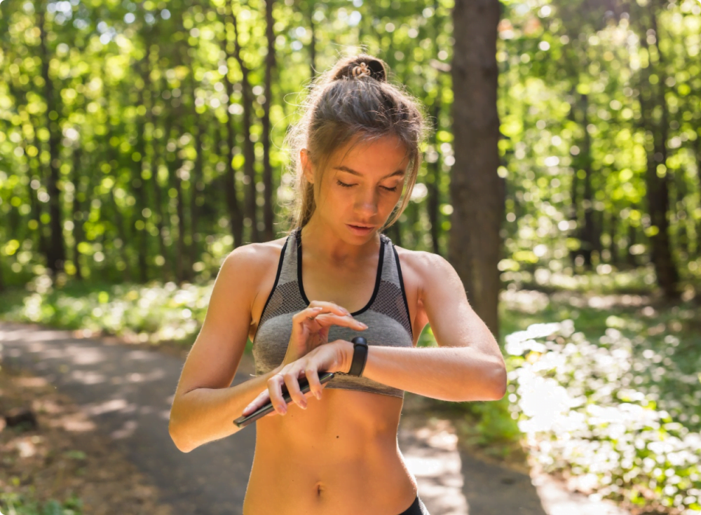 female runner looking at sports watch in woods