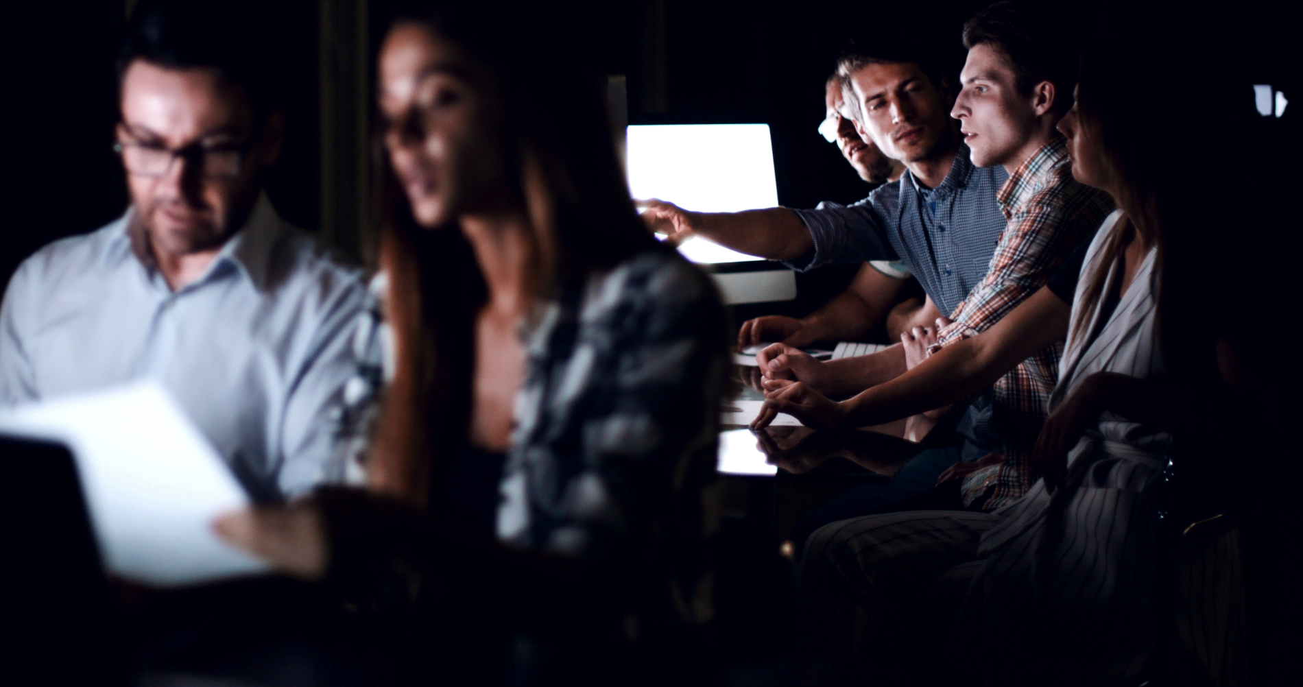 co workers looking at screen in a dark room
